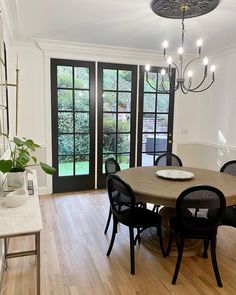 a dining room table with black chairs and a chandelier