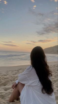 a woman sitting on top of a sandy beach