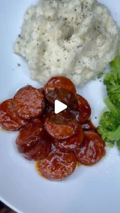 a white plate topped with broccoli and meat covered in gravy next to mashed potatoes