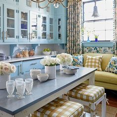 a kitchen with blue cabinets and white flowers on the counter top, along with two yellow checkered stools