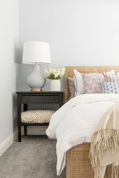 a bedroom with a bed, night stand and lamp on the side table in front of it