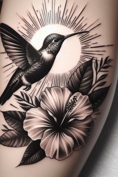 a tattoo with a hummingbird and flowers on the thigh, in black and white