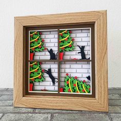 an image of a window with cats and christmas trees on the windowsill in front of a brick wall