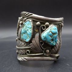 "VINTAGE NAVAJO BRACELET DESCRIPTION: This colossal bracelet features an abundance of applied sterling silver leaves, scrolls and raindrops, on heavy gauge sterling silver with chisel stamped rolled edges. Five specimens of natural Kingman turquoise adorn the cuff. PLEASE NOTE: 2 of the cabs have slight cracks (please see photos). The turquoise cabochons are all secure in their bezels. This impressive bracelet will be a cherished addition to your collection of fine vintage Native American jewelr Silver Patina Jewelry For Weddings, Vintage Hallmarked Antique Silver Cuff Bracelet, Elegant Silver Bracelets With Patina, Elegant Silver Patina Bracelets, Formal Silver Jewelry With Patina, Vintage Sterling Silver Cuff Bracelet For Ceremonial Occasions, Vintage Sterling Silver Cuff Bangle, Vintage Turquoise Sterling Silver Bracelet, Vintage Sterling Silver Cuff Jewelry