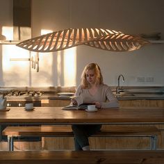 a woman sitting at a kitchen table reading a book