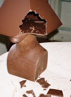 a piece of chocolate sitting on top of a table next to a broken lamp shade