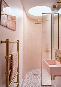 a pink bathroom with gold fixtures and tile flooring, along with an oval skylight