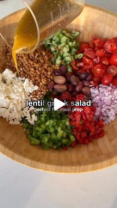 a wooden bowl filled with different types of vegetables and seasoning being poured on top