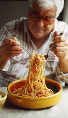 an old man eating noodles from a yellow bowl