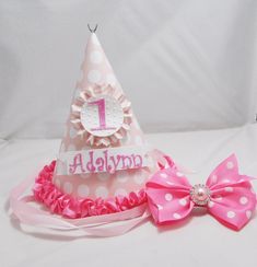 "This adorable party hat will sit upon her head. Birthday wishes are being said. THIS ITEM IS MADE TO ORDER! CONTACT ME BEFORE PURCHASING FOR ESTIMATED COMPLETION DATE. The hat was made out of high quality cardstock and digital patterned paper. The bow topper was made out of grosgrain ribbon and a pink jewel was added to finish it off. The bow is attached to an alligator clip and is removable to wear later. The number 1 was die cut, covered with glitter then attached to a white circle that was e Pink Smash Cake, Pink Smash Cakes, Sailor Baby Showers, Strawberry Party, 1st Birthday Shirts, Cake Photo, Pink Jewels, Hair Bow Sets