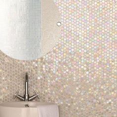 a bathroom sink sitting under a mirror next to a tiled wall with circles on it