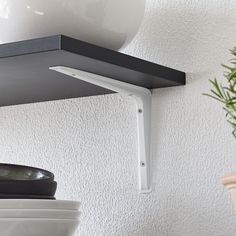 a potted plant sitting on top of a shelf next to a white vase and lamp