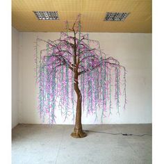 a tree with purple and green vines hanging from it's trunk in an empty room