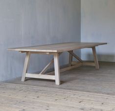 a wooden table sitting on top of a hard wood floor next to a gray wall