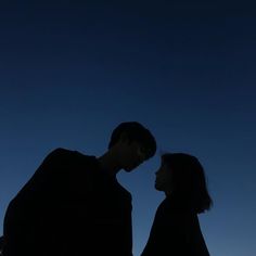 two people standing next to each other under a blue sky with the moon in the background