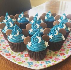 cupcakes with blue frosting and mickey mouse ears on a colorful floral plate