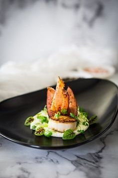 a black plate topped with food on top of a marble countertop next to a white furnishing