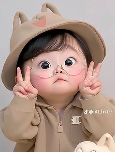 a young child wearing glasses and a brown hoodie is making the peace sign with her hands