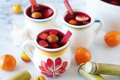 two mugs filled with fruit and vegetables on a table