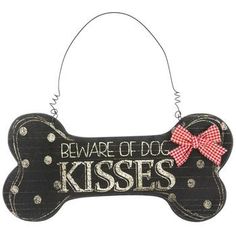 a wooden sign that says beware of dog kisses with a red bow on it