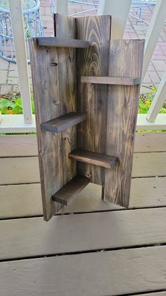 a bird house made out of wood on a porch with the door open and shelves built into it