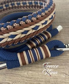 two blue and brown braided bracelets sitting on top of a wooden table next to a pen