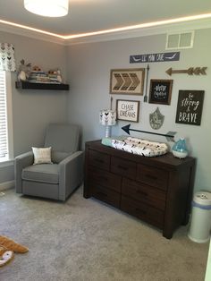 a baby's room with a gray chair and some pictures on the wall