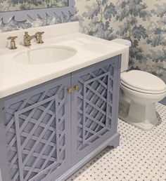 a white toilet sitting next to a sink in a bathroom under a mirror with blue flowers on it