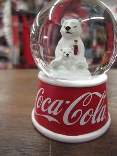 a coca cola snow globe with a polar bear in it on top of a wooden table