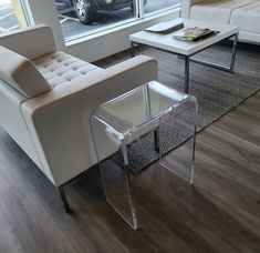 a living room filled with furniture next to a large window and a white couch sitting on top of a hard wood floor