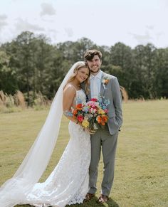 a bride and groom standing in the grass