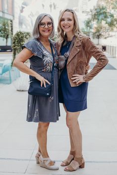 two women standing next to each other on a sidewalk