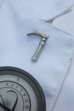 a small wrench sitting on the lapel of a dress shirt with a pocket watch