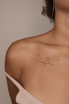 the back of a woman's shoulder with a small bird tattoo on her left side