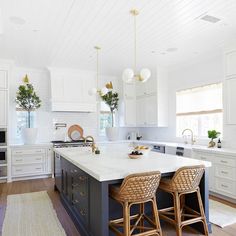 a kitchen with two stools in front of an island and white cabinets on the wall