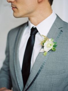 a man in a gray suit with a flower on his lapel