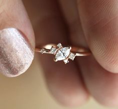 a close up of a person's hand holding a ring with two diamonds on it