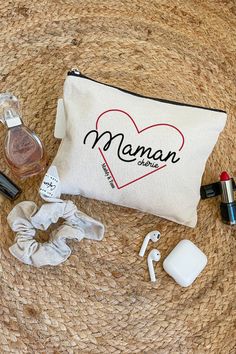 the contents of a personal care bag laid out on top of a straw mat, including an earbud, nail polish and lipstick