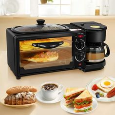 there is a toaster oven with food in it on the counter next to plates and cups