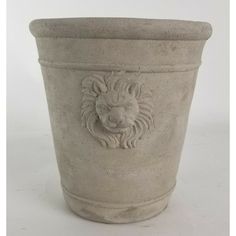 a stone planter with a lion head on the front and sides, sitting against a white background