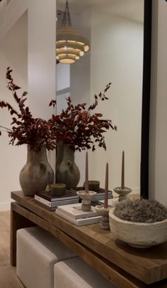 two vases with flowers and candles sit on a table in front of a mirror