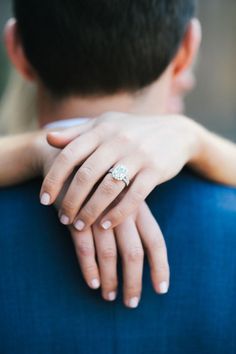 a man and woman holding each other with their hands on the back of his shoulder