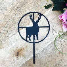 a metal deer head mounted to the side of a wooden table next to pink flowers