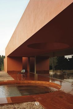 an outdoor swimming pool in front of a large red building with glass doors on the side