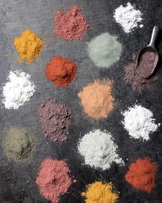 several different colored powders and a spoon on the ground