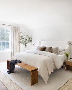 a bedroom with a bed, nightstands and a plant in the window sill