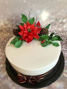 a white cake decorated with poinsettis and pine cones