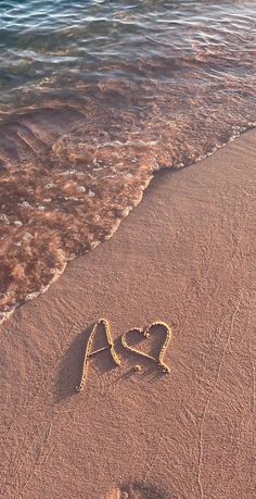 the word love is written in the sand at the beach with waves coming towards it