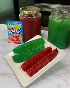 some pickles are sitting on a plate next to jars of jelly and gummy bears