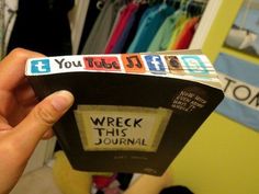 a person holding up a book with words on it in front of a closet full of clothes